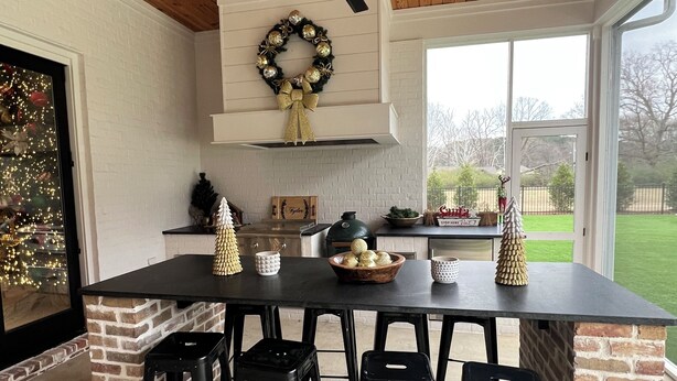 A kitchen with a brick island, black bar stools, a ceiling fan, and a wreath on the wall. - SPACIOUS 4-bdrm sleeps 10+,heated porch & tv’s, pool,hot tub,play room (Oxford)