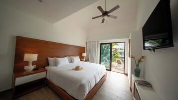 A hotel room with a large bed, a ceiling fan, a TV, and a view of the outdoors.