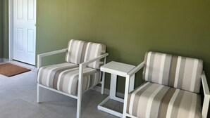 A room with two striped armchairs and a small white table, a white door, and a green wall. - ROSE COTTAGE-Tranquility steps from Grace Bay Beach and Grace Bay Strip! (Grace Bay)