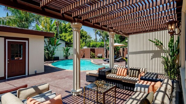 Ein überdachter Außenbereich mit Pool, Sitzgelegenheiten und einer Pergola.