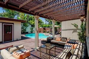 Un espace extérieur abrité comprenant une piscine, des sièges et une pergola.