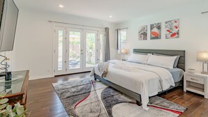 Ein Schlafzimmer mit Bett, Nachttischen, einer Glasvitrine und Blick durch die Schiebetüren ins Freie.