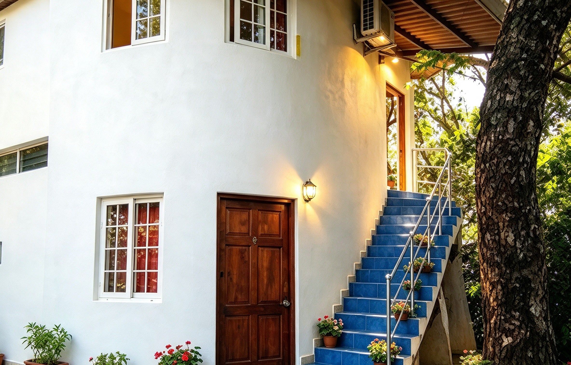Un bâtiment à deux étages avec une porte en bois, un escalier aux marches bleues et des plantes en pot.