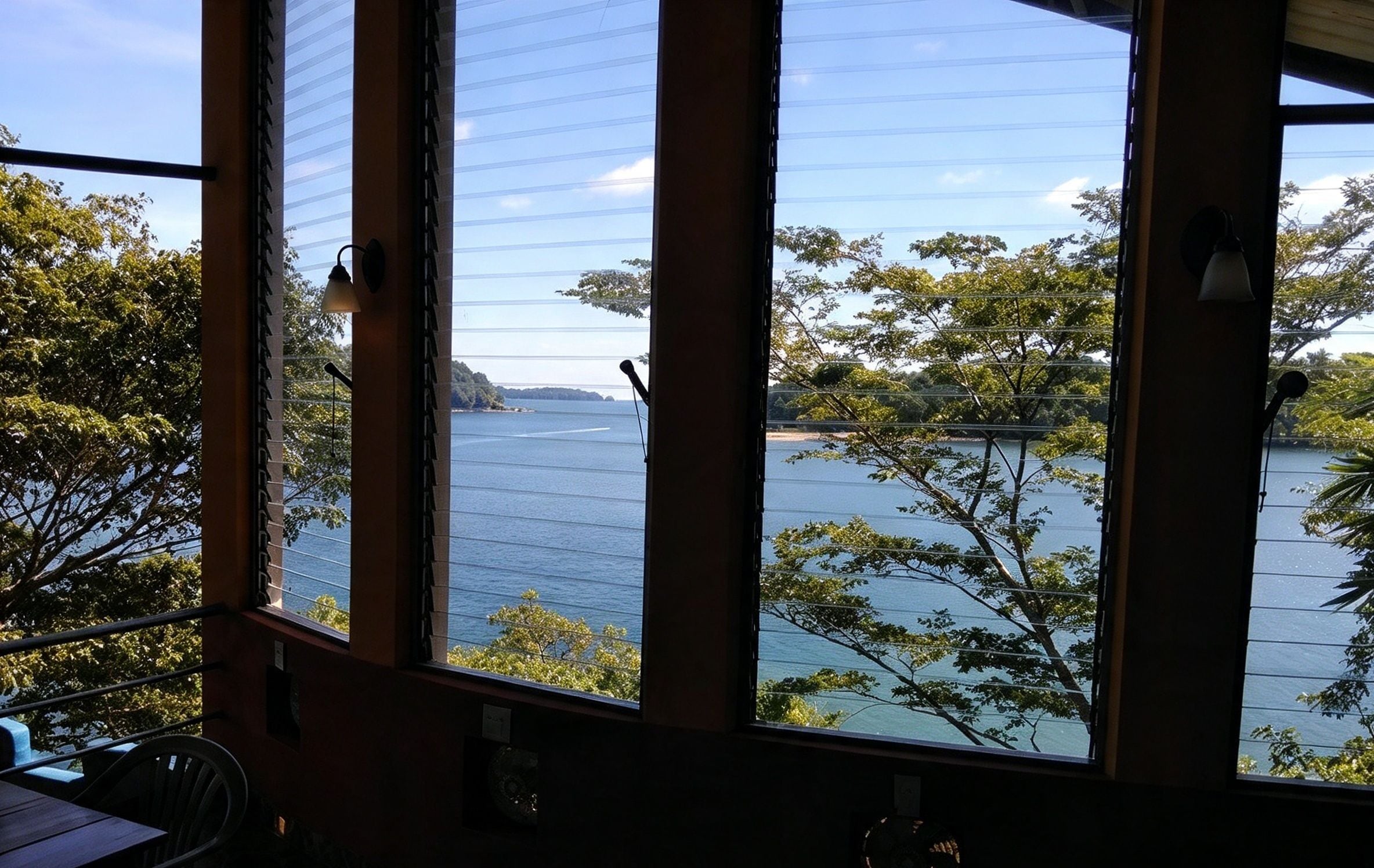 A room with large windows overlooking a body of water and trees.