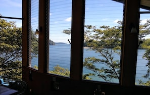 Ein Zimmer mit großen Fenstern und Blick auf ein Gewässer und Bäume.