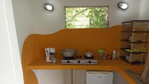 A compact kitchen with a gas stove, a small refrigerator, and a window with a view of greenery. - HOTEL BOCA BRAVA LODGE (Chiriqui)