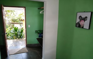 Un couloir aux murs verts, une porte donnant sur l’extérieur, un tableau encadré représentant un koala et un sol carrelé.