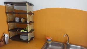 A kitchen with a sink, a shelf with dishes, and a spice rack. - HOTEL BOCA BRAVA LODGE (Chiriqui)