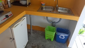 A compact kitchen with a sink, a small refrigerator, and two waste bins labeled for organic and recyclable materials. - HOTEL BOCA BRAVA LODGE (Chiriqui)