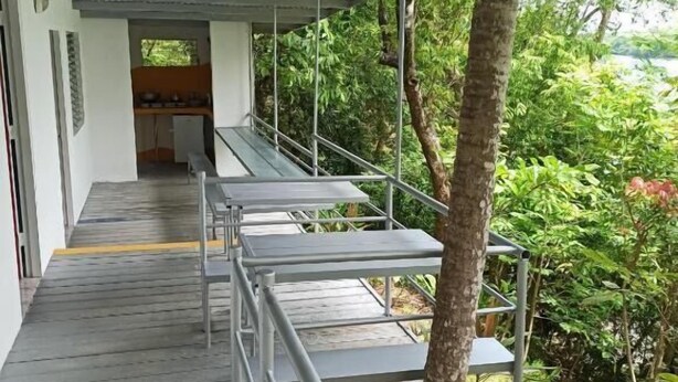 A covered outdoor area with a wooden deck, metal railings, and a view of a lush garden. - HOTEL BOCA BRAVA LODGE (Chiriqui)