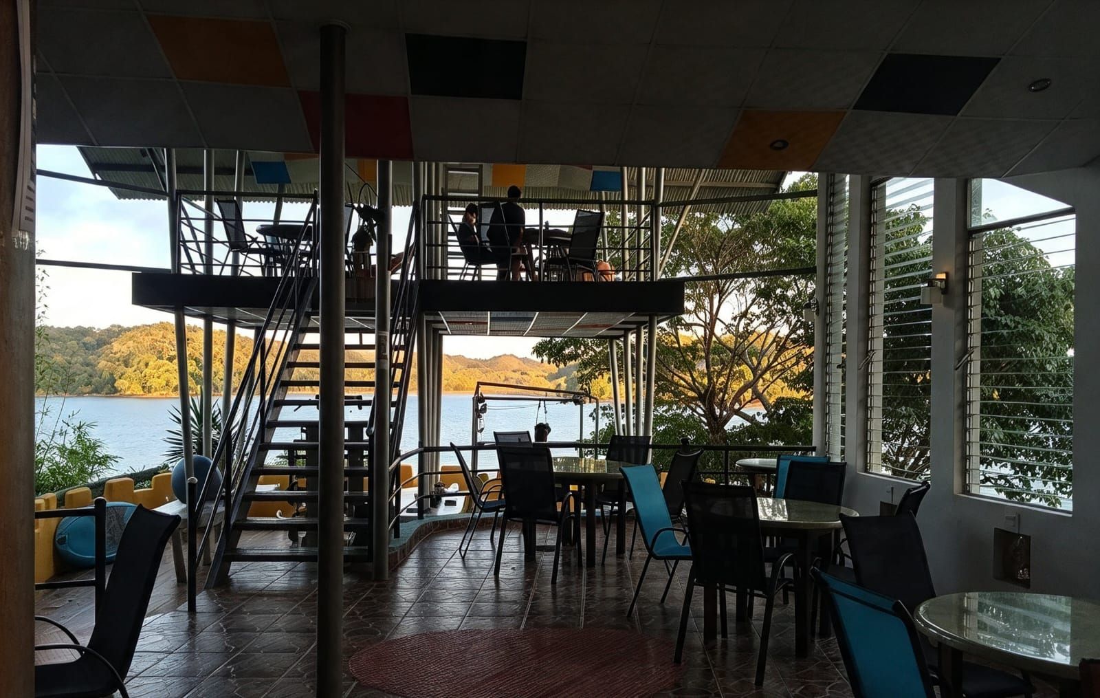 Un restaurant doté d’une terrasse offrant une vue sur un lac, avec un escalier et une vue panoramique sur les environs.