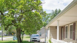 A house with a covered porch, a driveway, and a tree.