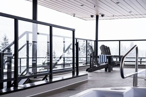 Un espace extérieur moderne doté d’une rambarde en verre, d’un escalier en métal et d’un coin salon avec des serviettes.