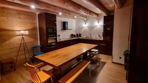 Une cuisine moderne avec des meubles de rangement en bois, une grande table en bois et des appareils électroménagers intégrés.