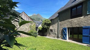 Une maison avec une façade en pierre, un toit de chaume et une pelouse bien entretenue.