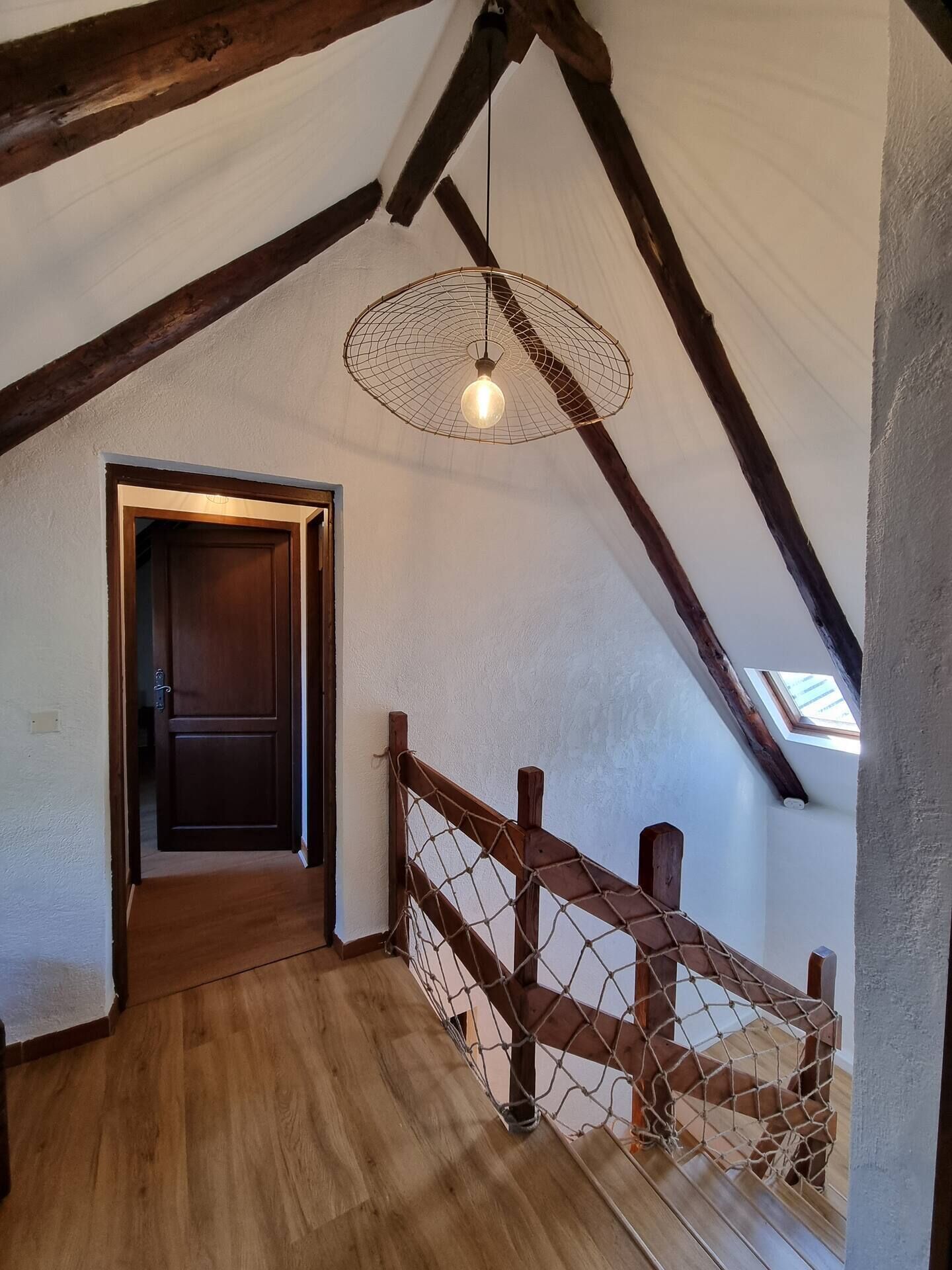 A wooden staircase with a netted railing leading to a door.