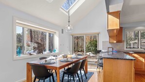 Une cuisine moderne avec un îlot central en bois, de grandes fenêtres et une lucarne.