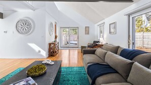 Un salon spacieux, doté d’un grand canapé, d’une table basse et offrant une vue sur l’extérieur grâce à une porte-fenêtre coulissante.