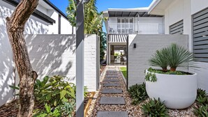 A modern house with a stone pathway, a large planter with a palm tree, and a view into the interior. - Casa Casuarina - Private pool & steps to the beach (Casuarina)