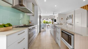 A modern kitchen with a stove, oven, and microwave. There is a dining area with a table and chairs, and a view of the outdoors. - Casa Casuarina - Private pool & steps to the beach (Casuarina)