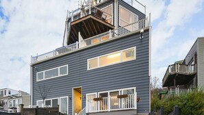 A modern two-story house with a balcony, a visible staircase, and a fenced backyard. - ★HostWise Stays★ Rooftop Deck | Garage | Balcony Views | Upscale! (Pittsburgh)