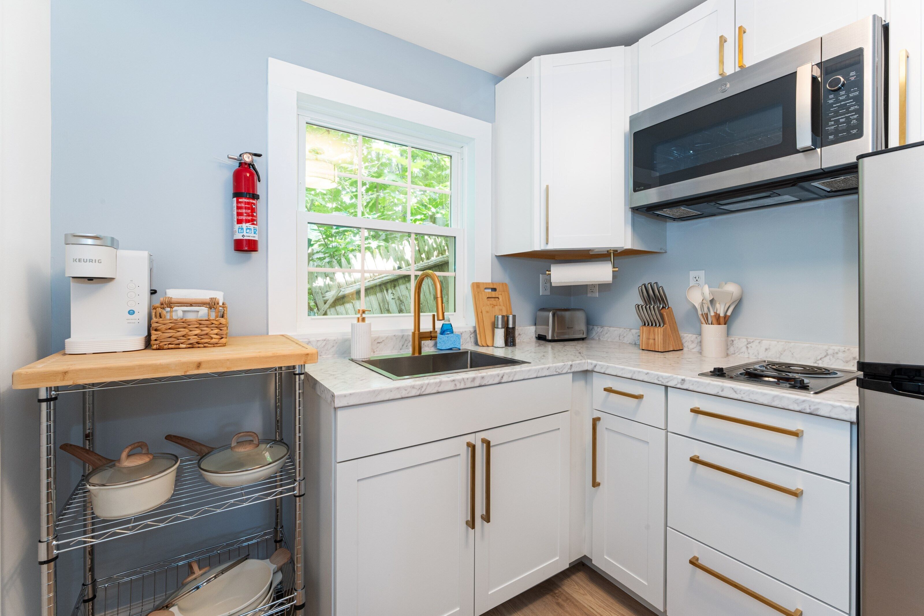 A modern kitchen with white cabinets, stainless steel appliances, and a window providing natural light.
