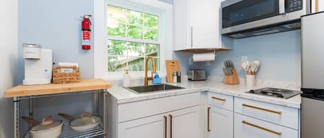 A modern kitchen with white cabinets, stainless steel appliances, and a window providing natural light.