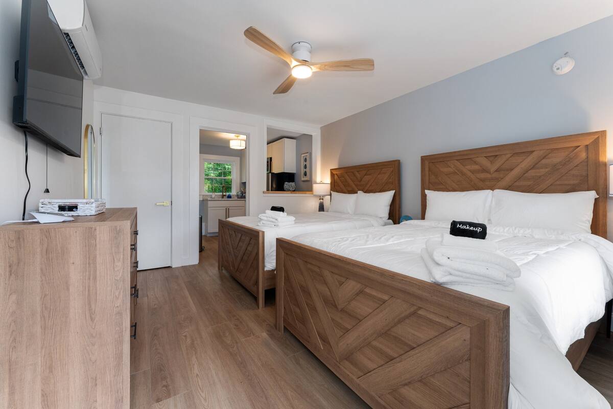 A hotel room with a wooden bed, a ceiling fan, a flat-screen TV, and a wooden desk.