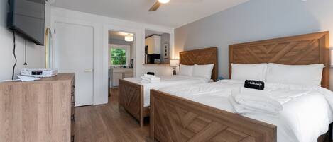 A hotel room with a wooden bed, a ceiling fan, a flat-screen TV, and a wooden desk.