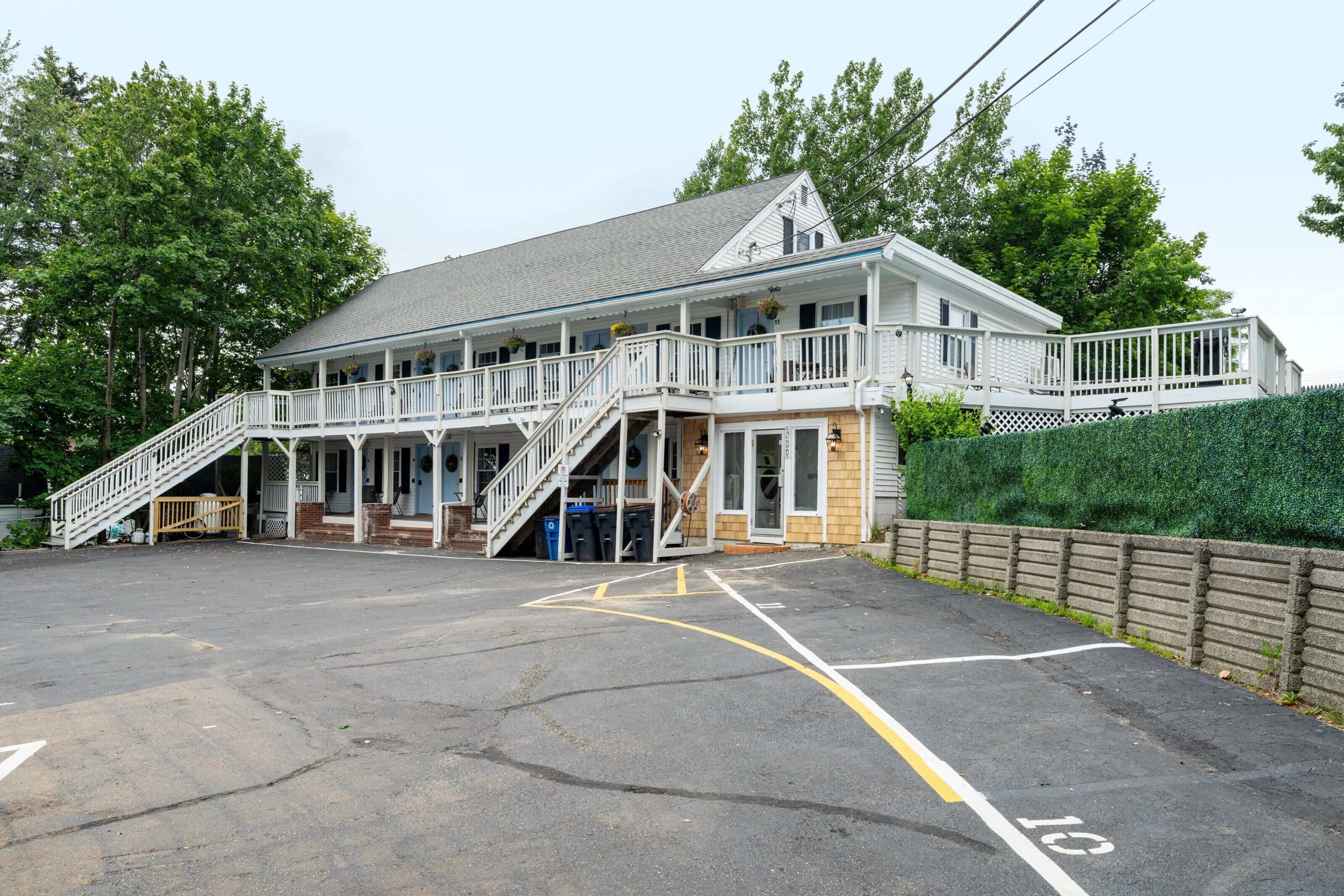 A two-story building with a balcony, a staircase, and a parking lot.