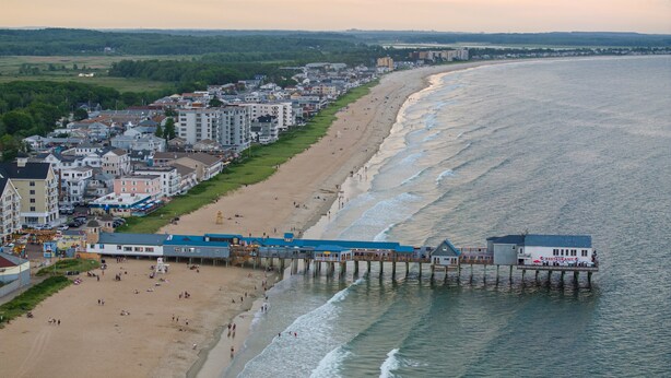 A coastal town with a beach, pier, and buildings along the shore. - Sunset Suites (Old Orchard Beach)