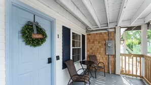 A porch with a blue door, a welcome wreath, and two chairs. - Sunset Suites (Old Orchard Beach)