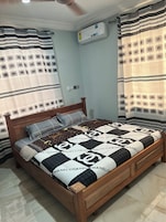 Un dormitorio con una cama de madera, colcha estampada y cortinas con diseños geométricos.