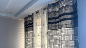 Ein Zimmer mit einem gemusterten Vorhang, einer weißen Decke und einem Lichtschalter an der Wand.