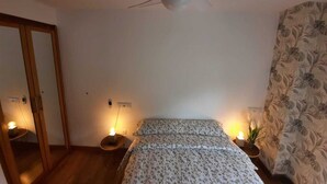 Un dormitorio con cama, ventilador de techo y dos lámparas de noche.
