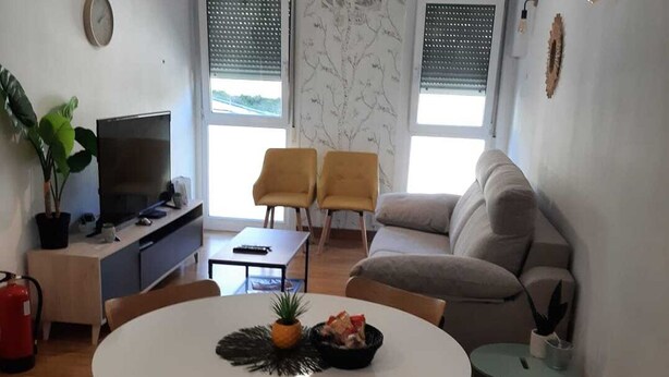 Un espacio habitable compacto con una mesa de comedor, dos sofás, un televisor y un ventilador de techo.