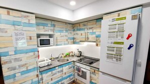 Una cocina compacta equipada con microondas, fregadero, estufa y refrigerador.