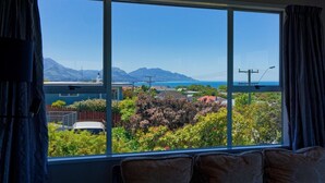Ein Zimmer mit großem Fenster und Blick auf eine Berglandschaft sowie ein Gewässer.