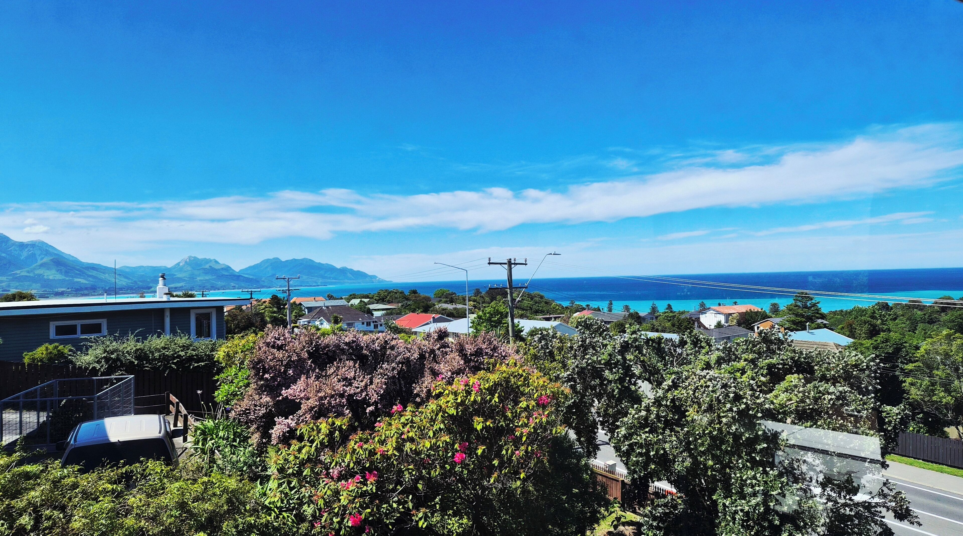 Una zona residencial con casas, una carretera y vistas al océano y las montañas.