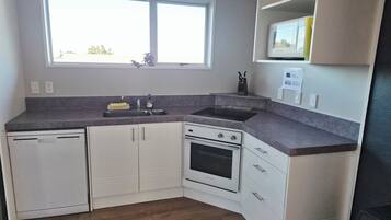 A kitchen with white cabinets, a built-in oven, a sink, and a window above the sink.