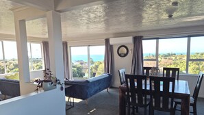 Ein Essbereich mit Meerblick, eine Couch und ein Tisch mit Stühlen.