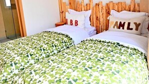 A double bed with a green and white patterned bedspread, two pillows with text, and a wooden headboard. - Superior Double with Terrace #1 (Tamraght Ouzdar,)