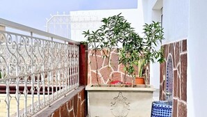 A small outdoor area with a metal railing, a potted plant, a stone bench, and a tiled floor. - Deluxe Double Room with Balcony #2 (Tamraght Ouzdar,)