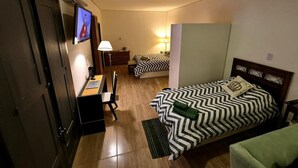 Een slaapkamer met een bed, bureau, stoel en televisie.
