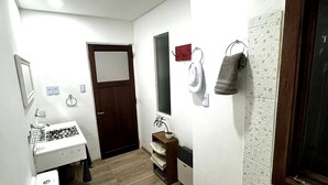 Een kleine badkamer met een wastafel, een toilet en een bidet. Er is een klein plankje met een potplant en een handdoekhouder met handdoeken.