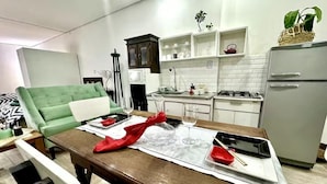 Een moderne keuken met witte kasten, een grijze koelkast en een eethoek met een houten tafel gedekt voor twee personen.