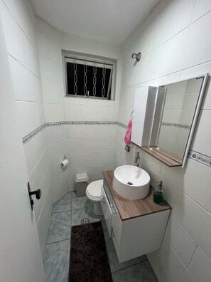 Un baño pequeño con inodoro, lavamanos y ventana.