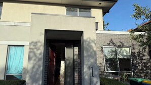 Una casa moderna de dos pisos con una entrada destacada, fachada de ladrillo y cielo despejado.