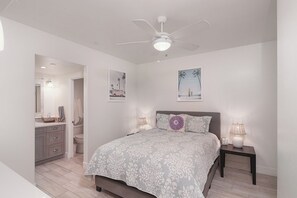 A bedroom with a bed, a ceiling fan, a nightstand with a lamp, and a bathroom with a vanity and toilet. - Charming 3-bedroom condo with AC in San Clemente (San Clemente)