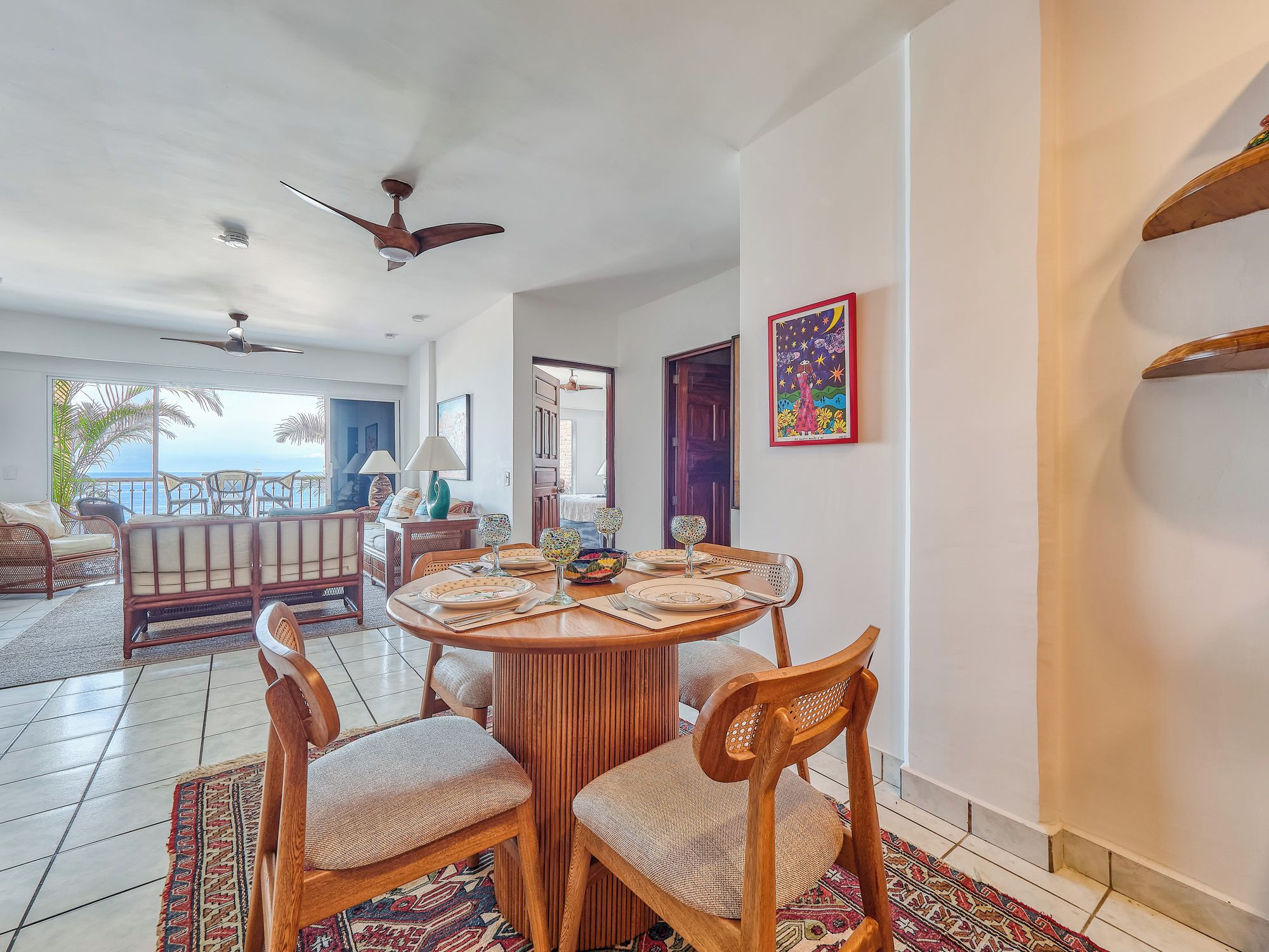 A dining area with a round table set for four, surrounded by wooden chairs with cushioned seats.